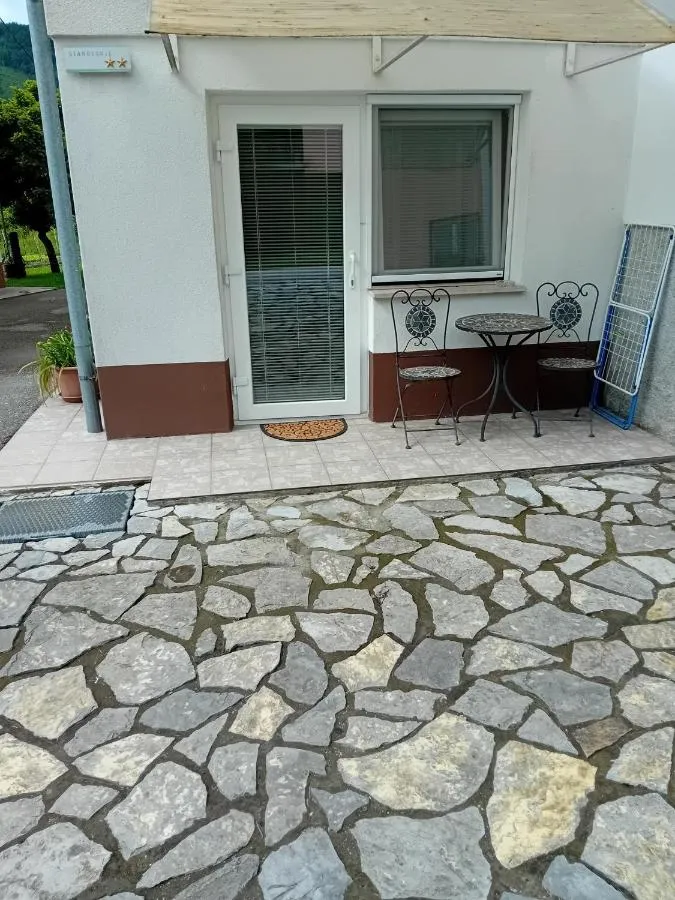 Vhod v sobo Milu: steklena vrata, mizica s stoli in tlakovana ploščad pred vrati